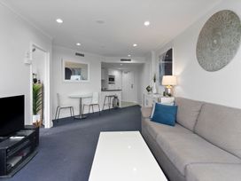 A living room with a sofa and dining area at an apartment in Auckland