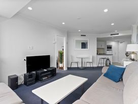 A living room with a television, sofa, and dining table at The Old Barn in Auckland