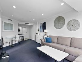 A living room with a sofa coffee table and dining table at The Old Barn in Auckland