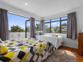 A bedroom with two beds and a balcony at Papamoa Beach in Papamoa