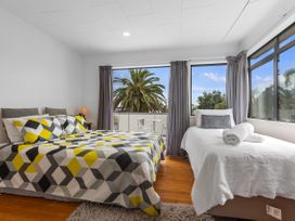 A bedroom with a bed and a single bed at Papamoa Beach in Papamoa