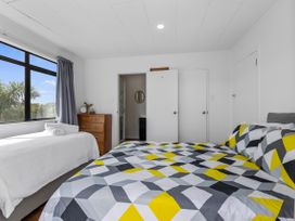 A bedroom with a bed and dresser at Papamoa Beach in Papamoa