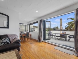 A living room with a dining area and patio access at Papamoa Beach in Papamoa