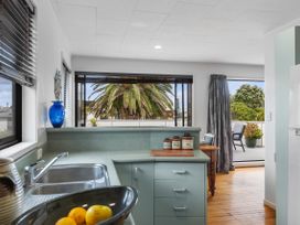 A kitchen with a sink and counter looking out to a palm tree at Papamoa Beach in Papamoa