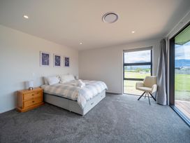A bedroom with a bed and a chair at Te Anau Holiday Home in Te Anau