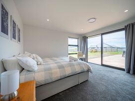 A bedroom with a bed and large windows at Te Anau Holiday Home in Te Anau
