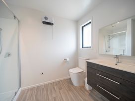 A bathroom featuring a shower, toilet, sink, and window at Te Anau Holiday Home in Te Anau