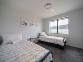 A bedroom with two beds and a side table at Te Anau Holiday Home in Te Anau