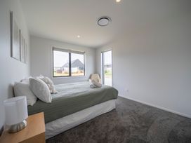 A bedroom with a bed and window at Te Anau Holiday Home in Te Anau