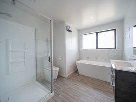 A bathroom with a shower, toilet, bathtub, and sink at Te Anau Holiday Home in Te Anau