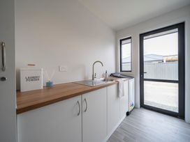 A laundry room with a sink and laundry machine at Te Anau Holiday Home in Te Anau