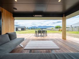 An outdoor patio with a sofa and dining table at Te Anau Holiday Home in Te Anau