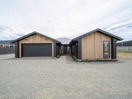 A house with a garage and pathway at Te Anau Holiday Home in Te Anau