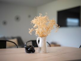 A dining room with a vase of dried flowers on a table at Te Anau Holiday Home in Te Anau