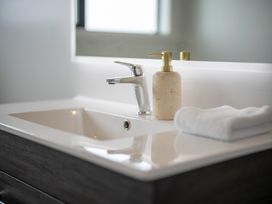 A sink with a faucet and soap dispenser at Te Anau Holiday Home in Te Anau