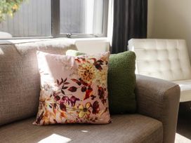 A couch with floral and green pillows in a living room at New Plymouth