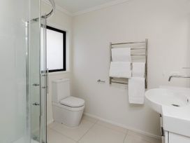 A bathroom with a shower, toilet, towel rack, and sink at Strandon Coastal Townhouse - New Plymouth