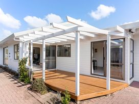 An outdoor area with a wooden deck and pergola at Whangamata