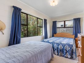 A bedroom with two beds and windows at Whangamata