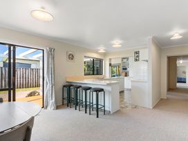 A kitchen with bar stools and a window at Whangamata