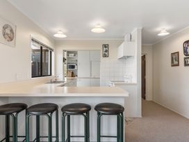 A kitchen with a counter and bar stools at Whangamata in Whangamata