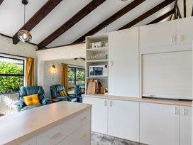 A kitchen with a microwave and chairs at Whangamata in Whangamata