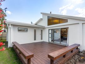 A house exterior with a wooden deck and windows at Whangamata