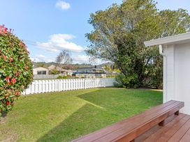 A garden with grass and a bench at Whangamata
