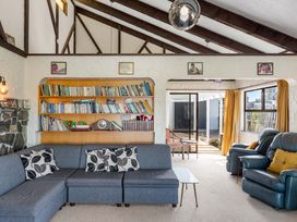 A living room with a sofa and bookshelf at Whangamata