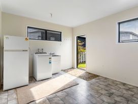 A laundry room with a washing machine and fridge at Whangamata