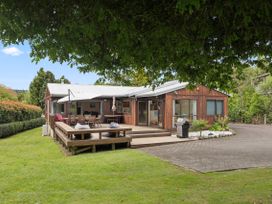 An exterior view of a house with a deck and dining area at Paradise At 471 - Rotorua Holiday Home in Rotorua