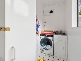 A laundry room with a washing machine and a sink at Paradise At 471 - Rotorua Holiday Home in Rotorua