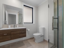 A bathroom with a sink, mirror, toilet, and shower at Papamoa