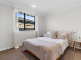 A bedroom with a bed, nightstand, and window at Papamoa