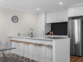 A kitchen with bar stools and a refrigerator at Papamoa
