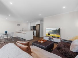 A living room with a kitchen island and bar stools at Papamoa