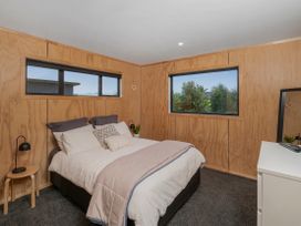 A bedroom with a bed and windows at Whitianga