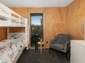 A bedroom with a bunk bed and a chair at Whitianga