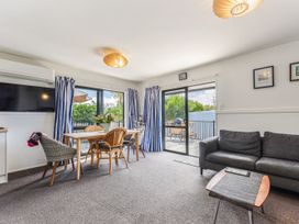 A living room with a sofa, dining table and television at Casa Verde - Mapua Holiday Home, Mapua