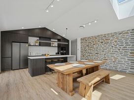 A kitchen with a wooden dining table and stone wall at Cromwell Holiday Home in Cromwell