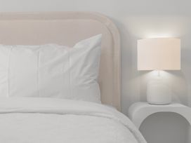 A bed with pillows and a lamp on a table at Sunrise on Vintage - Cromwell Holiday Home in Cromwell