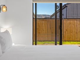 A bedroom with a bed and lamp viewing a fenced outdoor area at Sunrise on Vintage - Cromwell