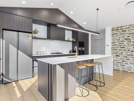 A kitchen with a fridge and bar stools at Sunrise on Vintage - Cromwell Holiday Home in Cromwell