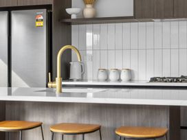 A kitchen with a refrigerator, stove, and storage jars at Sunrise on Vintage - Cromwell Holiday Home, Cromwell