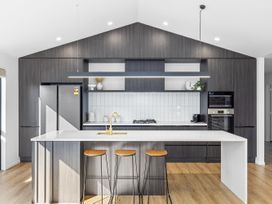 A kitchen with a refrigerator, sink, stove, and bar stools at Sunrise on Vintage - Cromwell