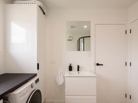 A bathroom with a washing machine and sink at Clyde Holiday Home in Clyde