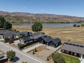 An aerial view of houses near a lake and mountains at Dancing Tussock Escape - Cromwell