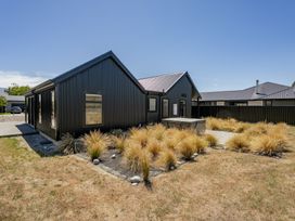 A house with a driveway and landscaped yard at Dancing Tussock Escape - Cromwell Holiday Home, Cromwell