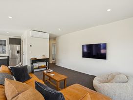 A living room with a sofa and television at Dancing Tussock Escape - Cromwell Holiday Home, Cromwell