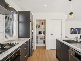 A kitchen with stove, refrigerator, and sink at Dancing Tussock Escape - Cromwell Holiday Home in Cromwell